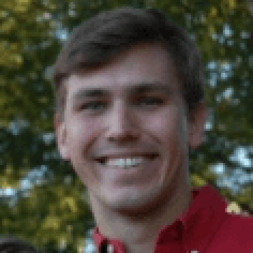 A man in red shirt smiling for the camera.