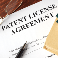 A pen and paper sitting on top of a patent license agreement.